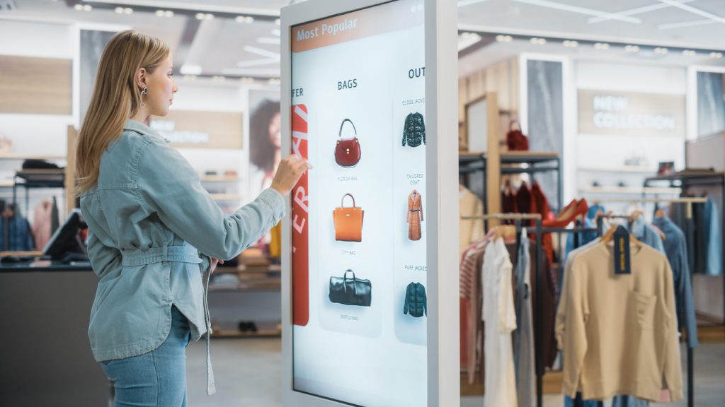 an image of a woman shopping in a store and interacting with a retail media network screen