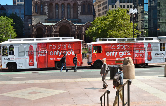 Image of a pair of wrapped trolleys advertising a beverage product on the streets of Boston
