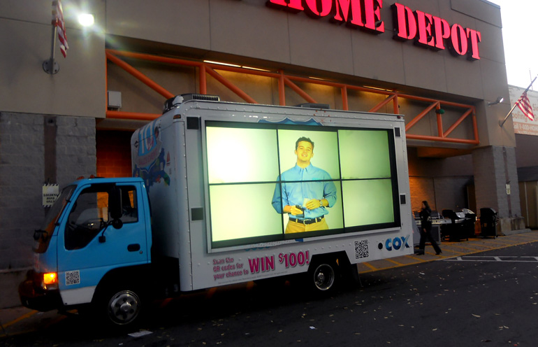 Image of a video display vehicle targeting customers at a retail location