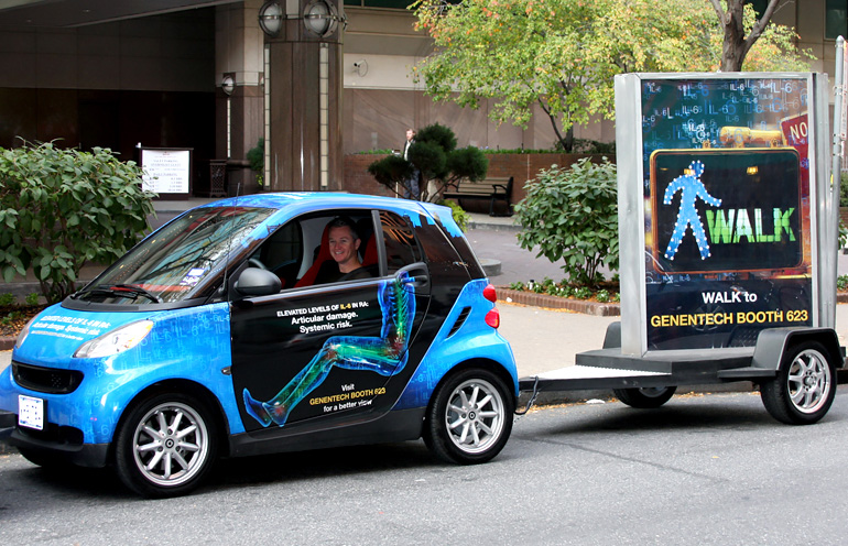 Image of a wrapped smart car towing a backlit advertising display in Philadelphia