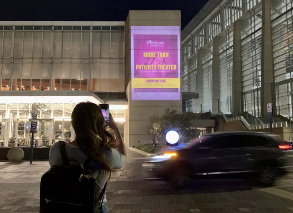 An image of an event attendee taking a picture of Out-of-home media for event marketing