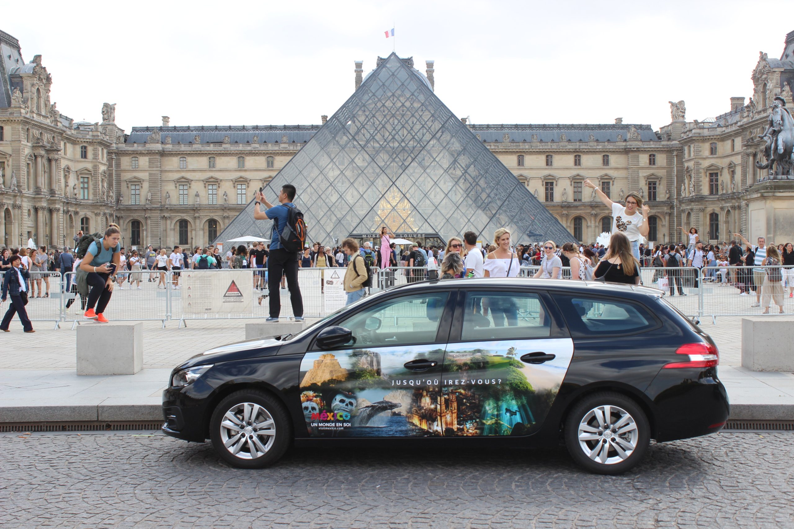 An image of a wrapped car in front of the Louvre museum in Paris
